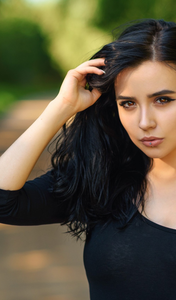 Красивая молодая девушка в черном с татуировкой на руке