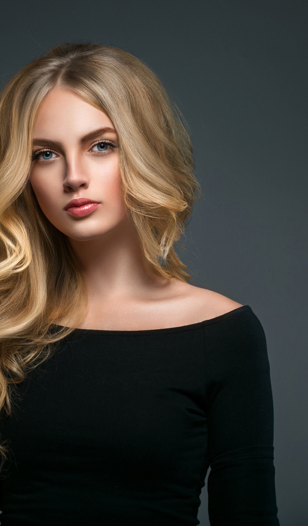 Красивая молодая девушка с длинными волосами в черном наряде на сером фоне