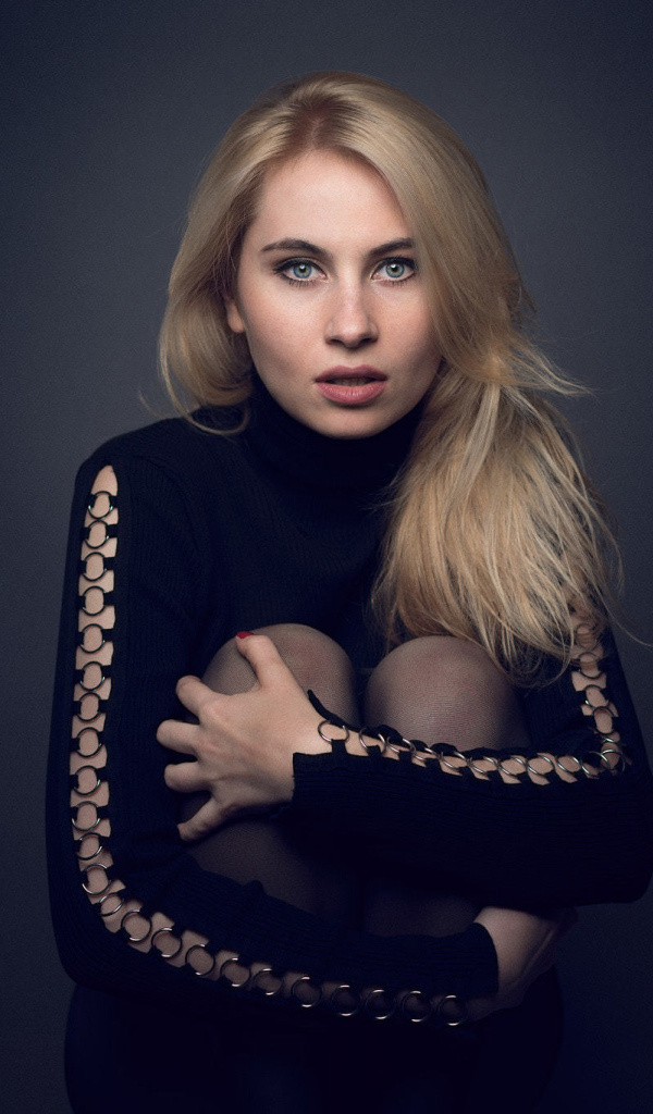 Блондинка в черном наряде на сером фоне