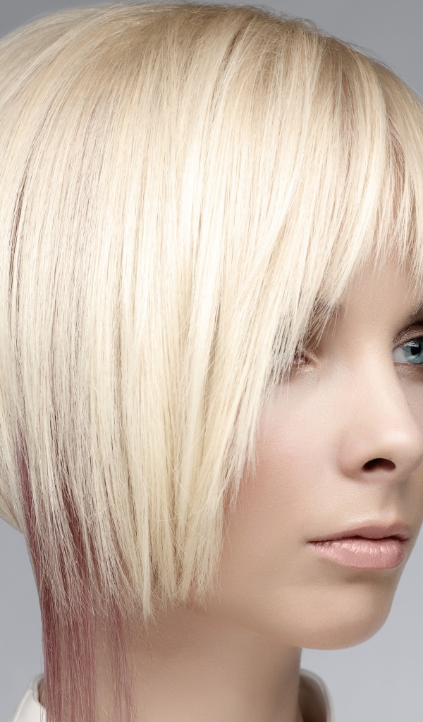 Голубоглазая девушка блондинка с короткой стрижкой на сером фоне