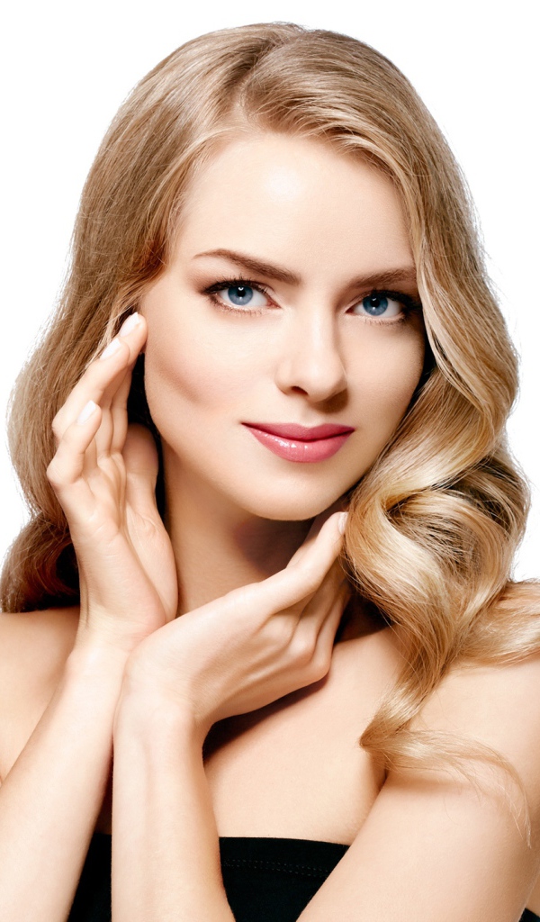 Голубоглазая блондинка с руками у лица на белом фоне