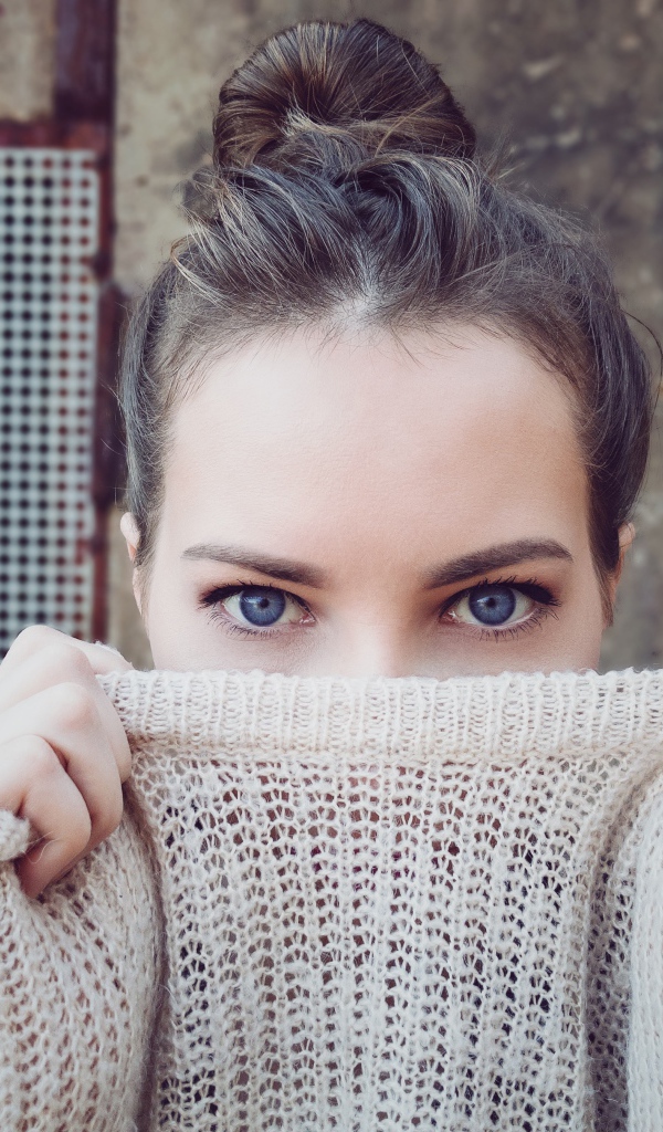 Голубоглазая девушка закрыла лицо свитером 