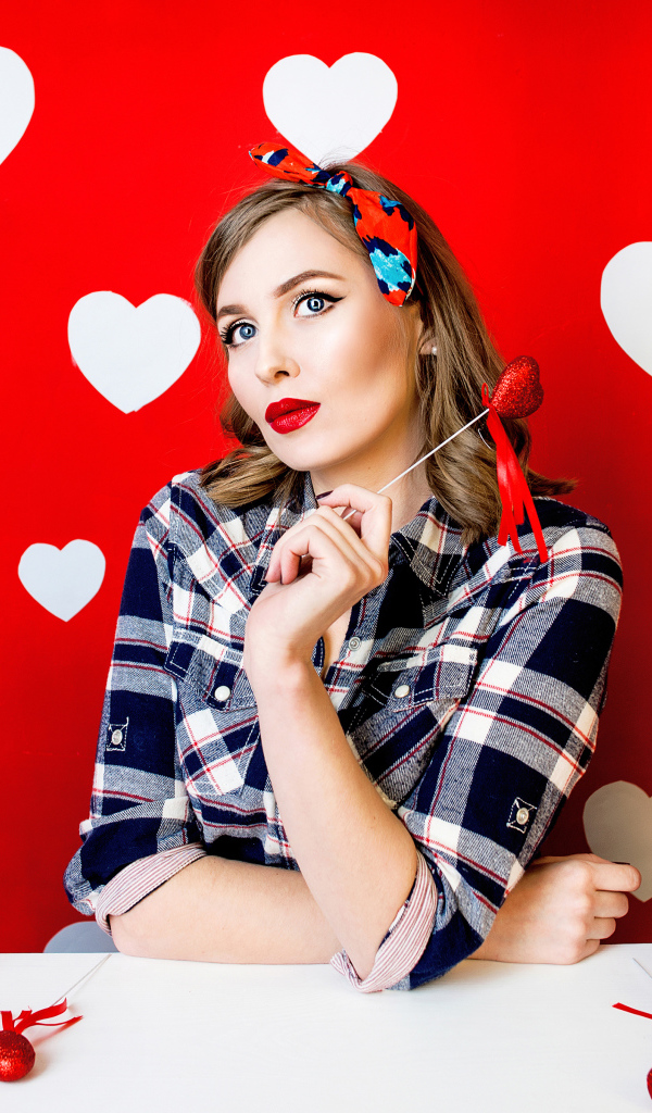 Яркая девушка за столом со сладостями на красном фоне с белыми сердечками 