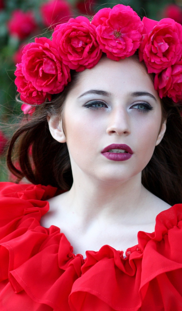 Яркая девушка в красном платье с венком из роз на голове
