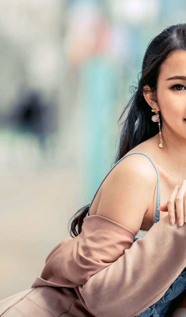 Очаровательная девушка азиатка сидит на лавке