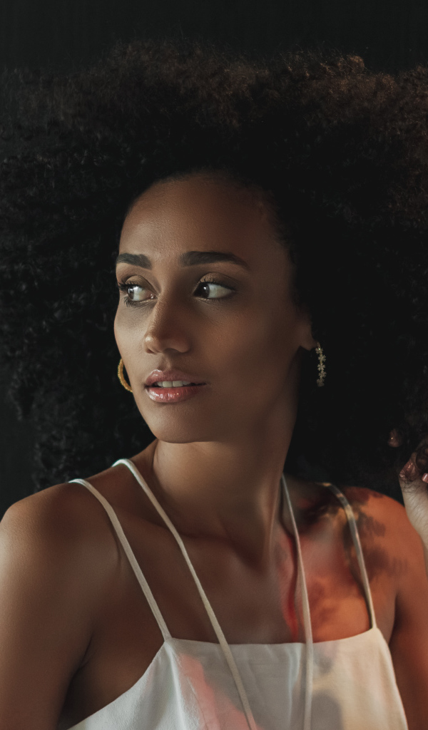 Темнокожая девушка с красивыми волосами на сером фоне