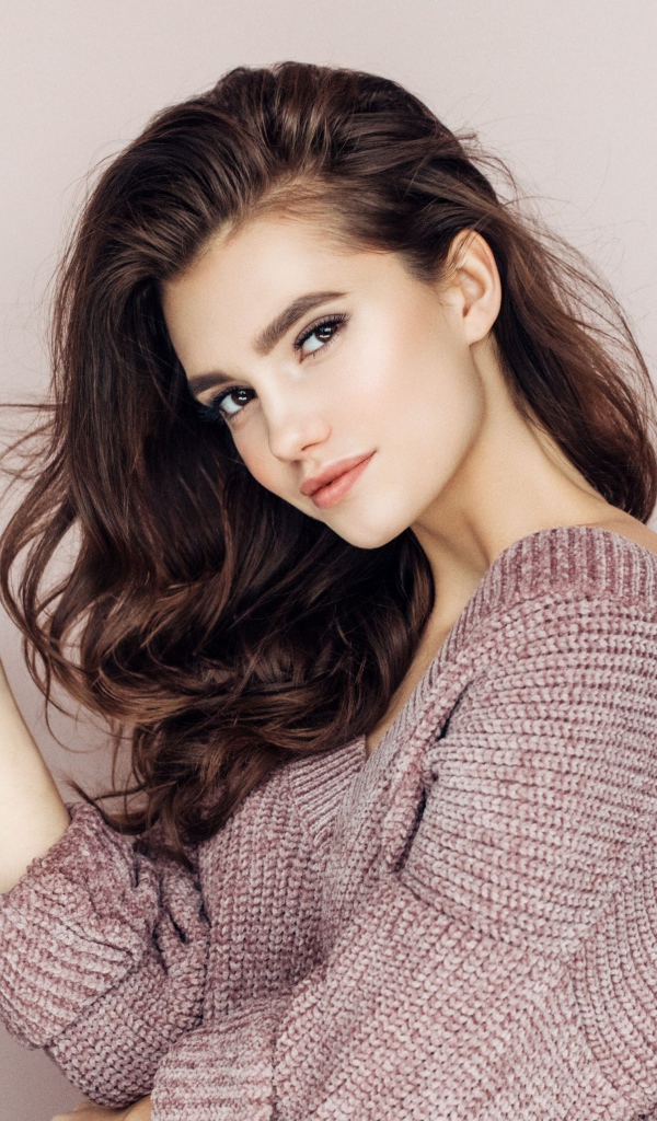 Нежная блондинка в свитере на сером фоне