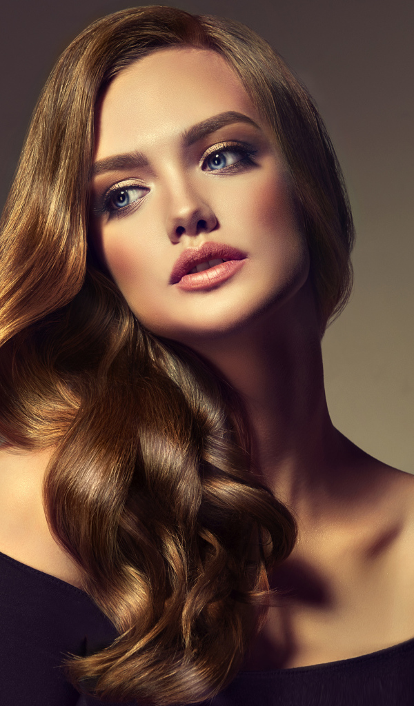 Нежная голубоглазая модель с длинными волосами на сером фоне