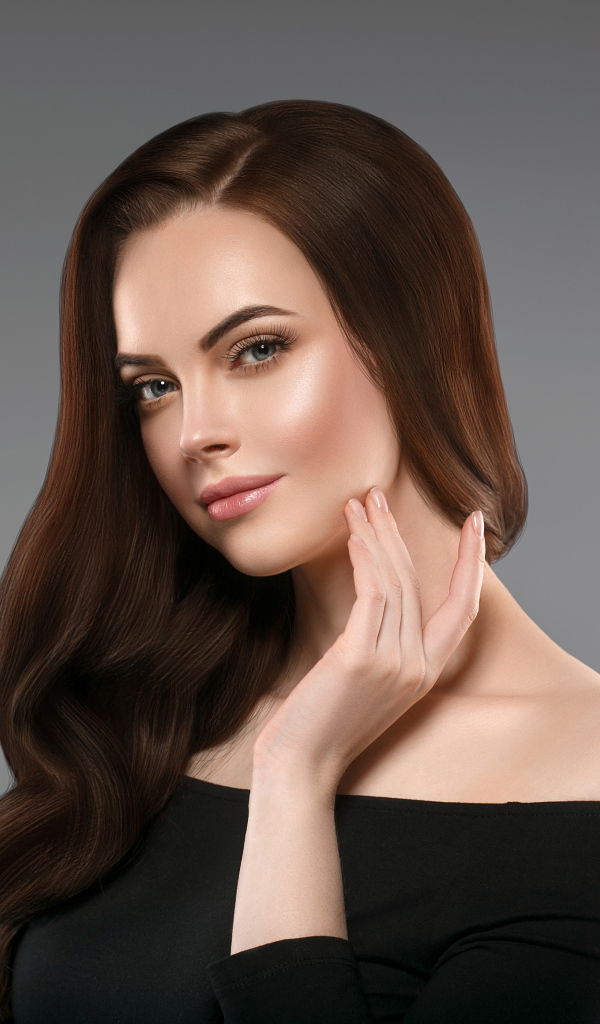 Нежная длинноволосая шатенка в черном платье на сером фоне