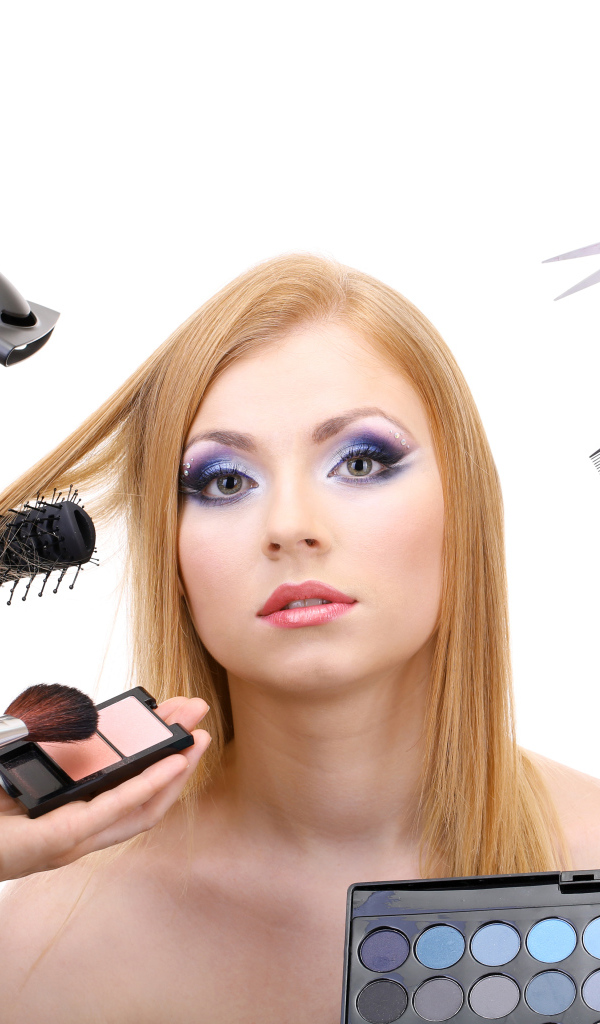 Девушке делают макияж и прическу на белом фоне