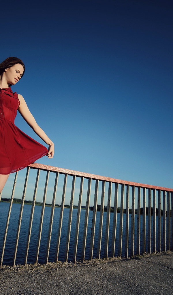 Девушка в коротком красном платье на мосту 