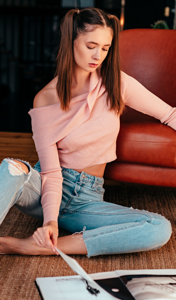 Девушка читает журнал на полу у кожаного кресла