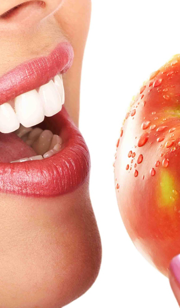 Девушка с красивыми белыми зубами кусает яблоко