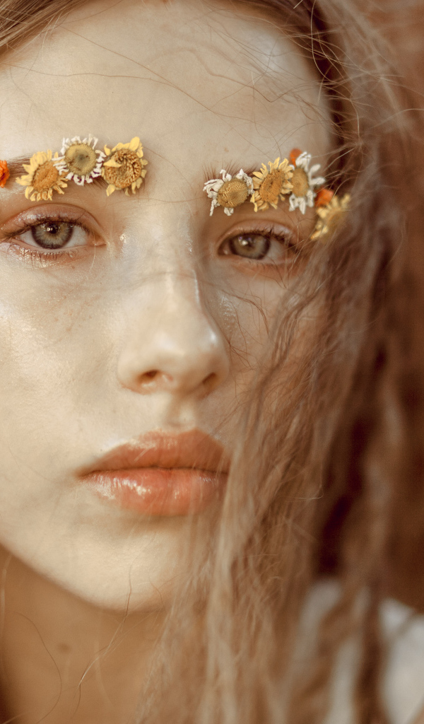 Девушка с цветами на бровях крупным планом