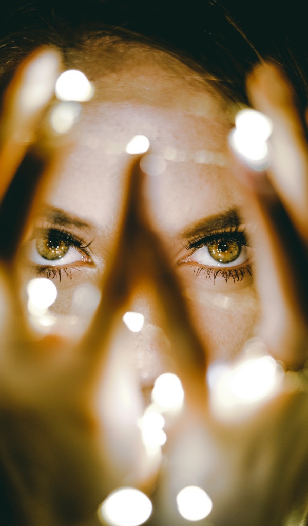 Руки с гирляндой у лица девушки