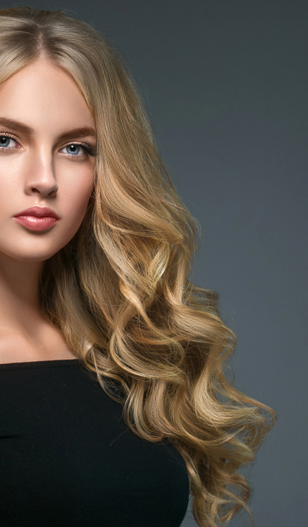 Длинноволосая блондинка с голубыми глазами на сером фоне