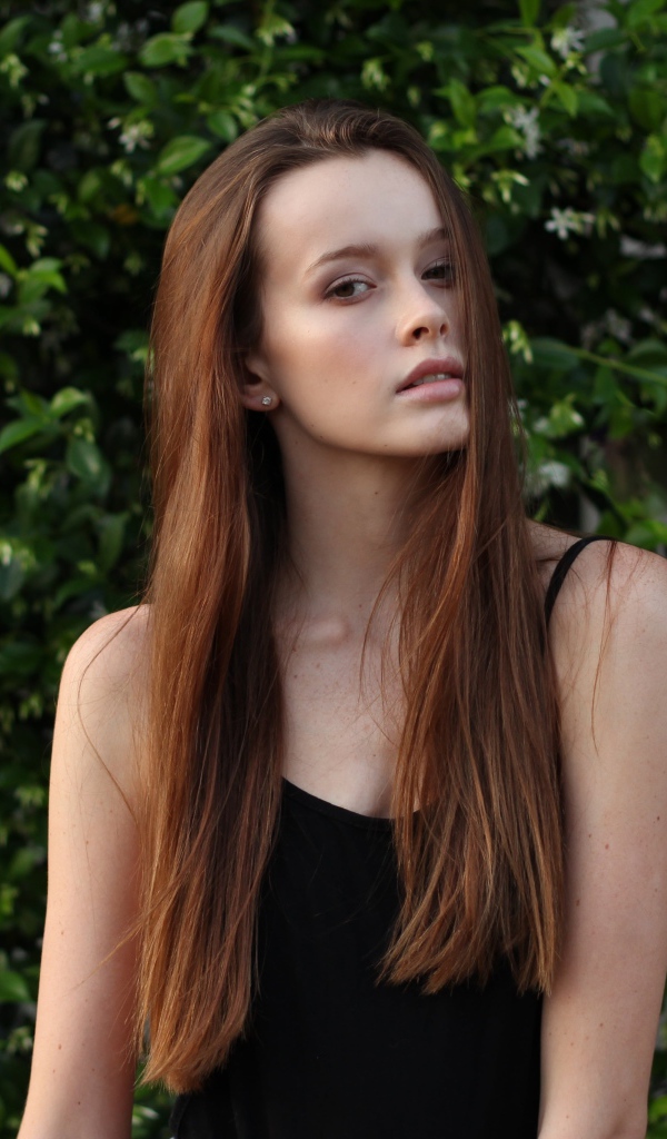 Длинноволосая шатенка на фоне зеленых зарослей