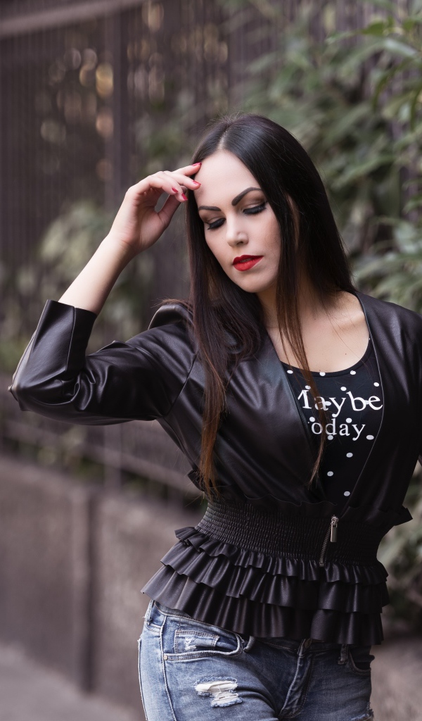 Длинноволосая брюнетка в черной куртке у забора