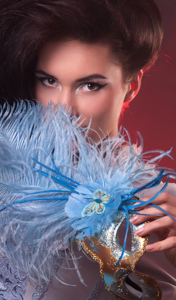 Длинноволосая девушка с маской с перьями в руке