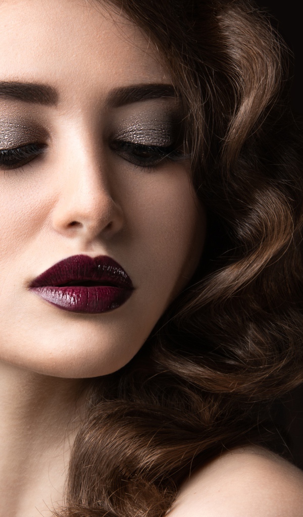 Длинноволосая девушка с ярким макияжем на черном фоне