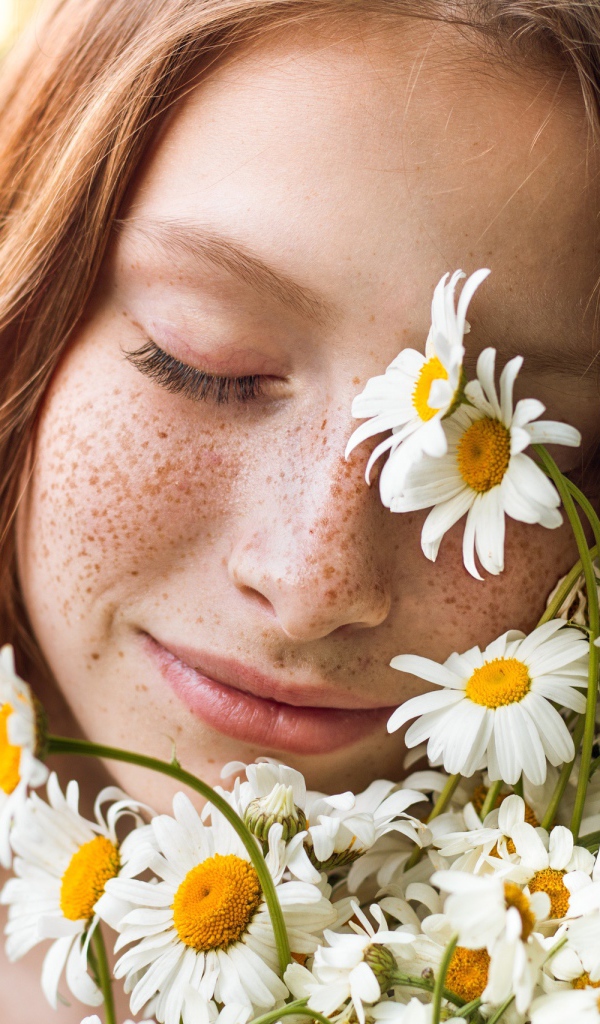 Рыжеволосая девушка с букетом ромашек