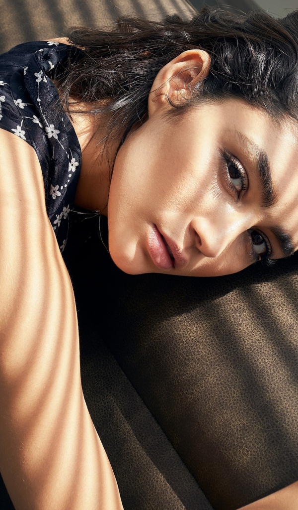 Грустная девушка брюнетка лежит на диване