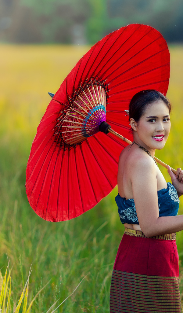 Улыбающаяся девушка азиатка с красным зонтом