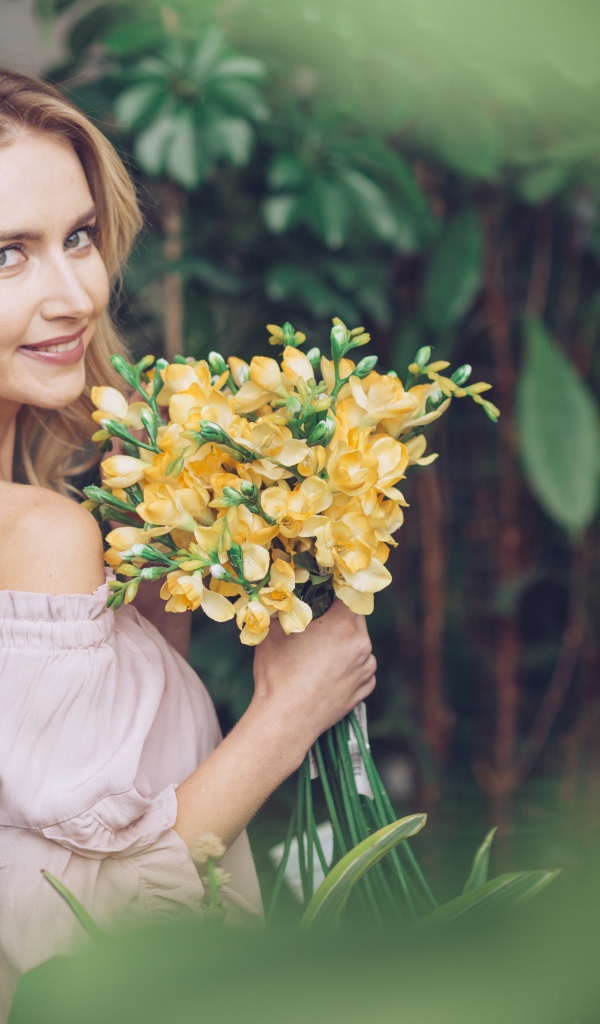 Улыбающаяся блондинка с букетом хризантем в руках