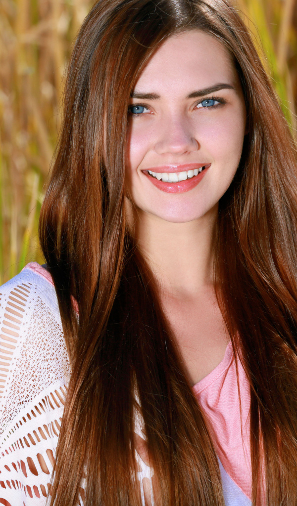 Улыбающаяся голубоглазая шатенка на поле