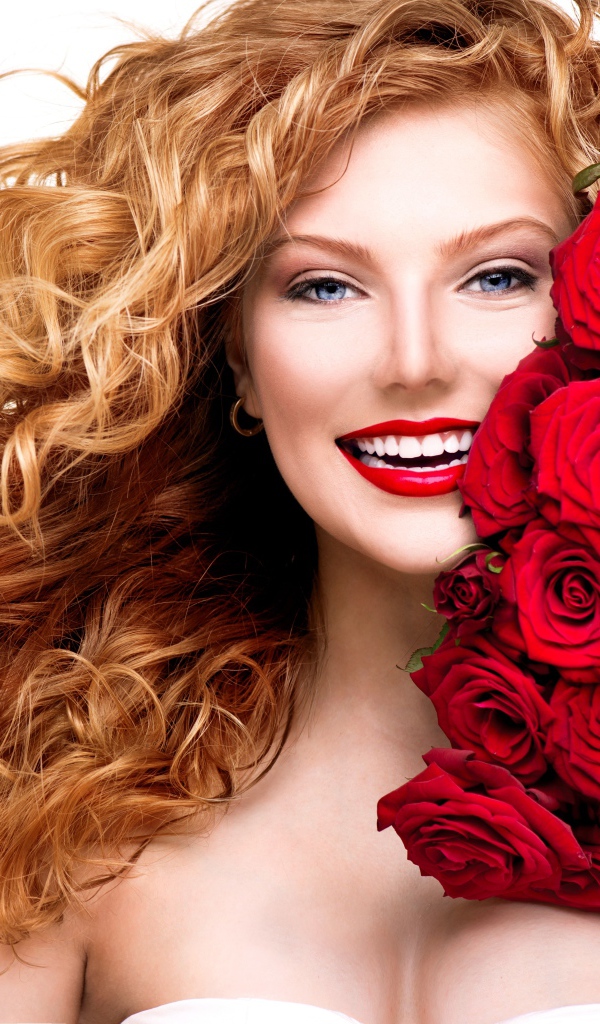 Улыбающаяся голубоглазая рыжеволосая девушка с букетом красных роз 