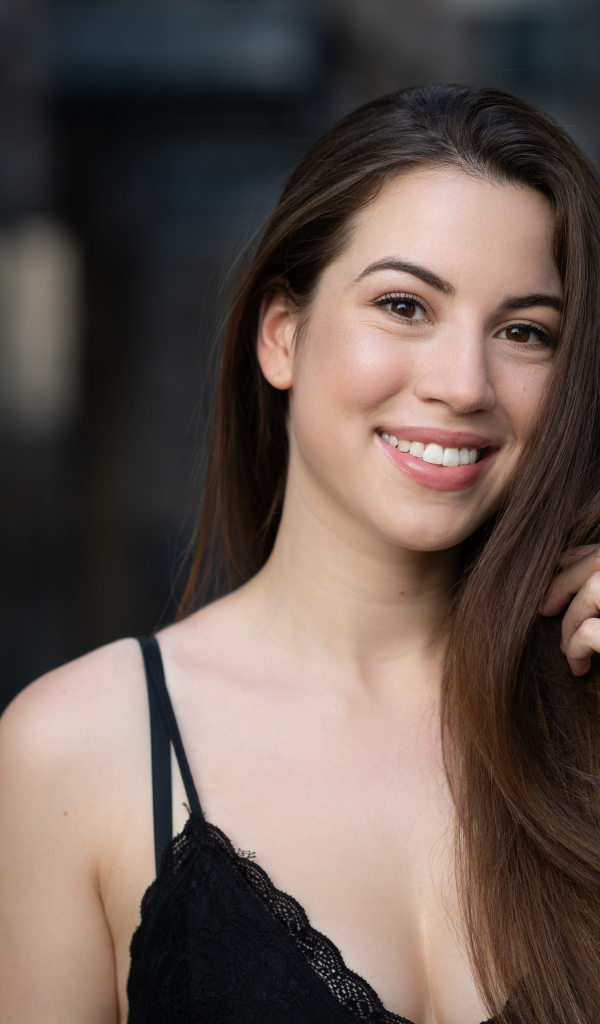 Улыбающаяся девушка держит длинные волосы