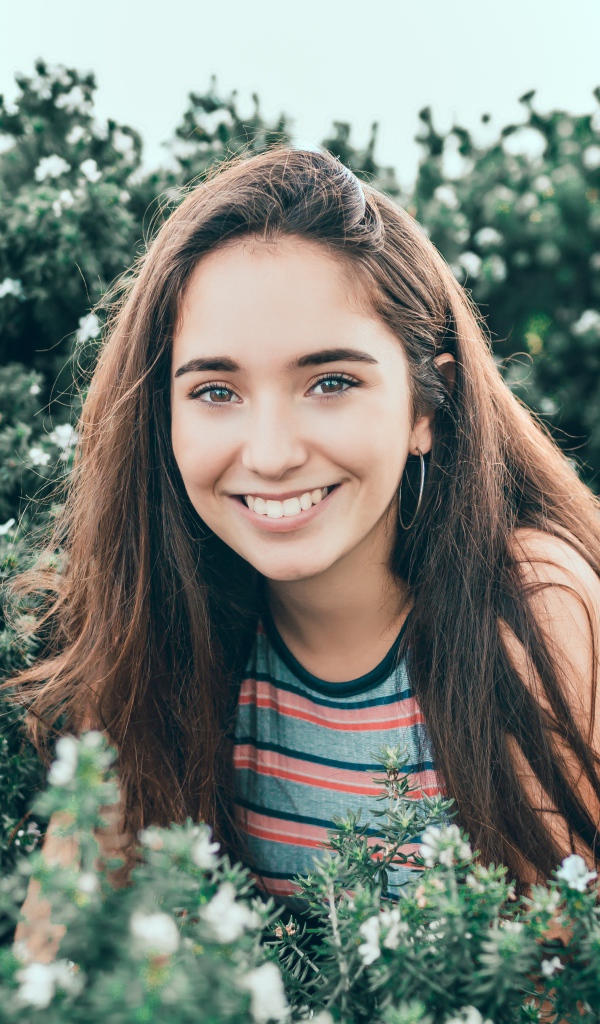 Улыбающаяся девушка сидит в зеленых зарослях 