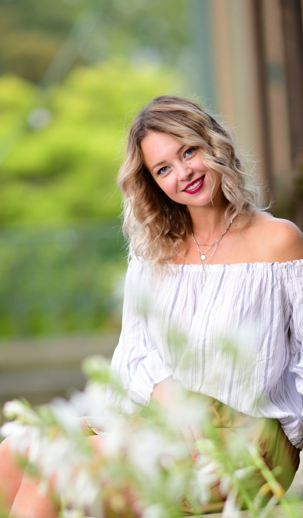 Улыбающаяся девушка сидит на ступенях