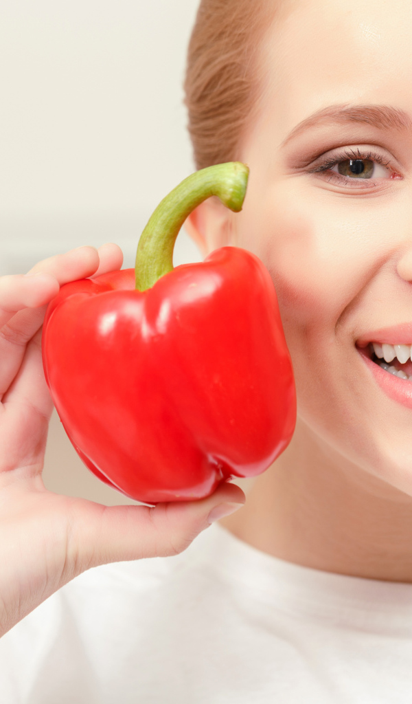 Улыбающаяся девушка с красным сладким перцем в руке