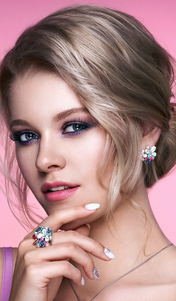 Стильная блондинка с прической на розовом фоне