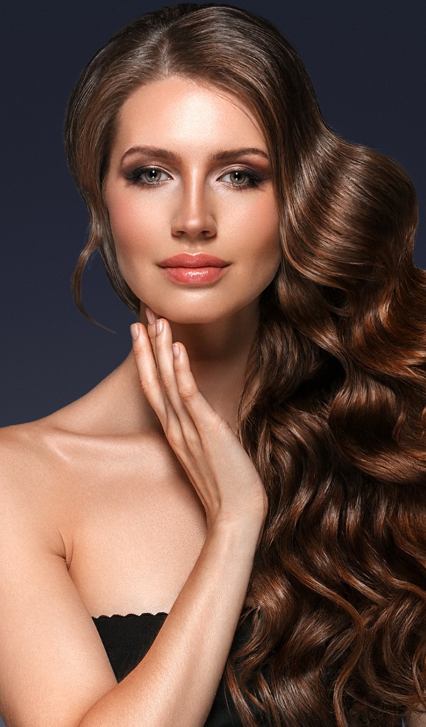 Стильная девушка с красивыми длинными волосами на сером фоне