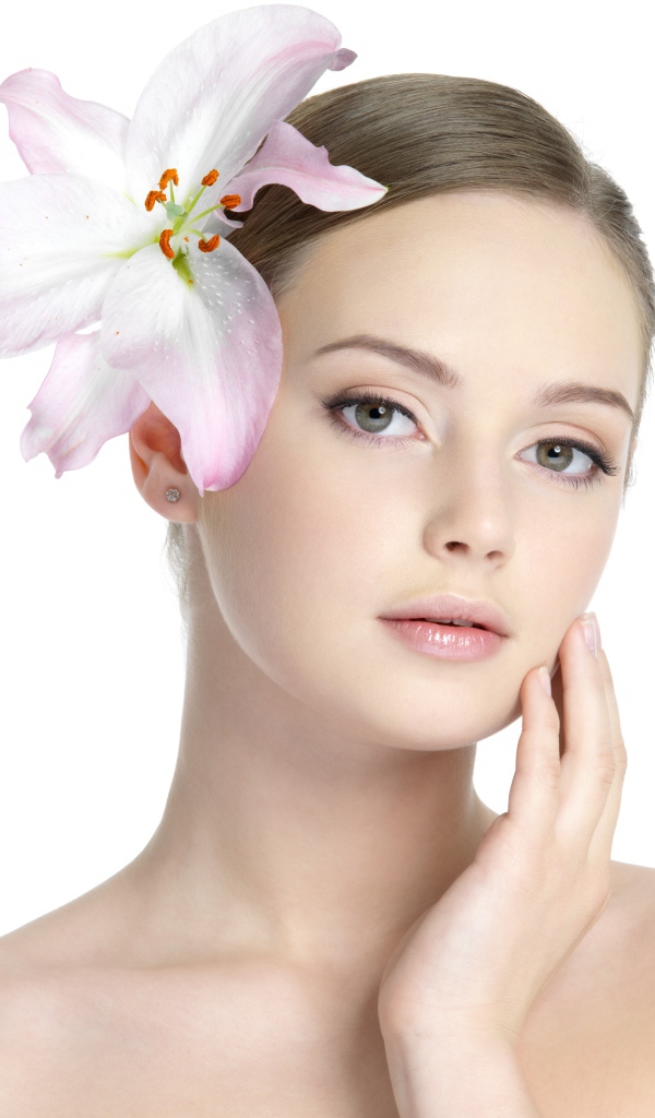 Нежная красивая девушка с лилией в волосах на белом фоне 