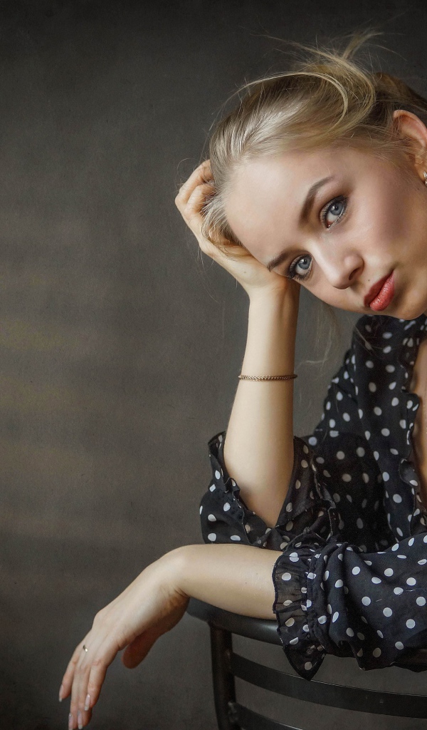 Нежная девушка блондинка сидит на стуле