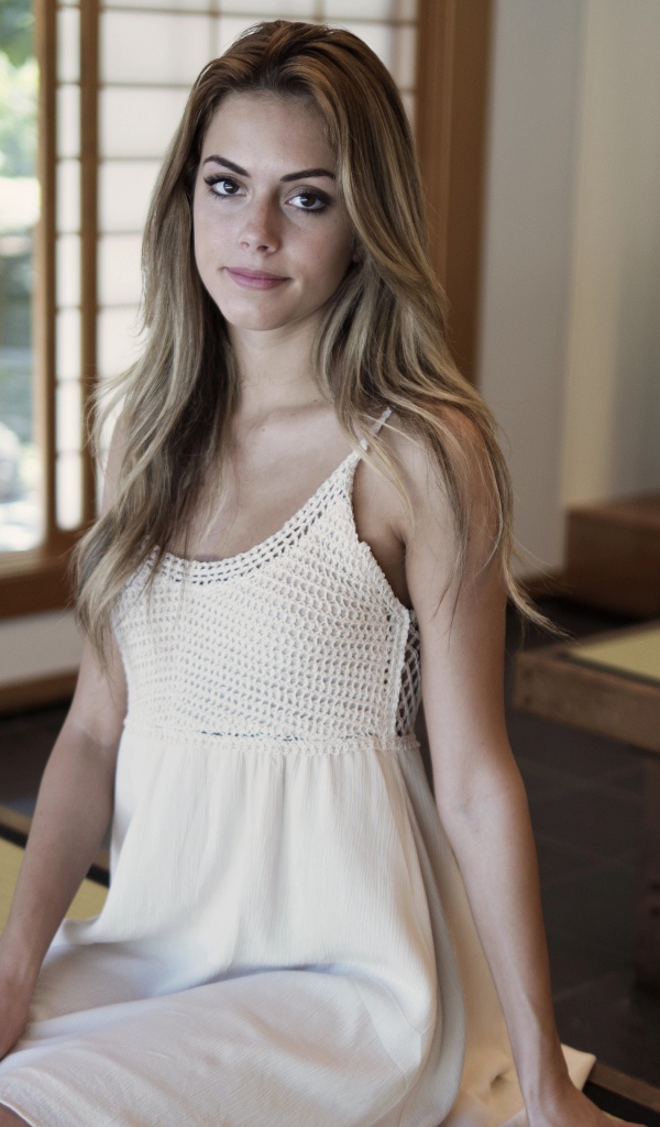 Девушка в белом сарафане сидит на лавке 