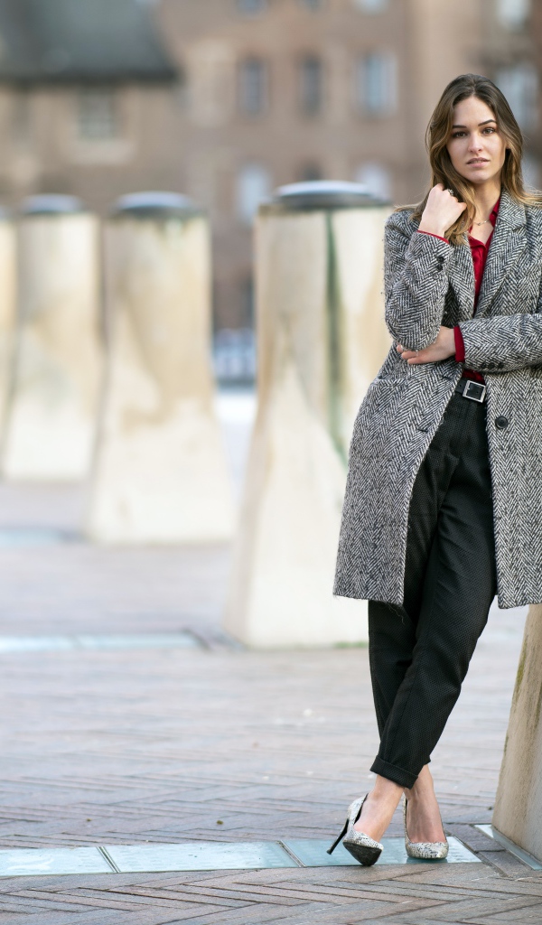 Девушка стоит в сером пальто 