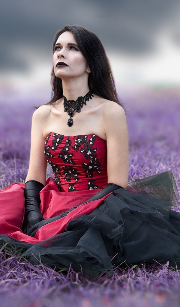 Девушка с макияжем в красивом платье сидит на траве