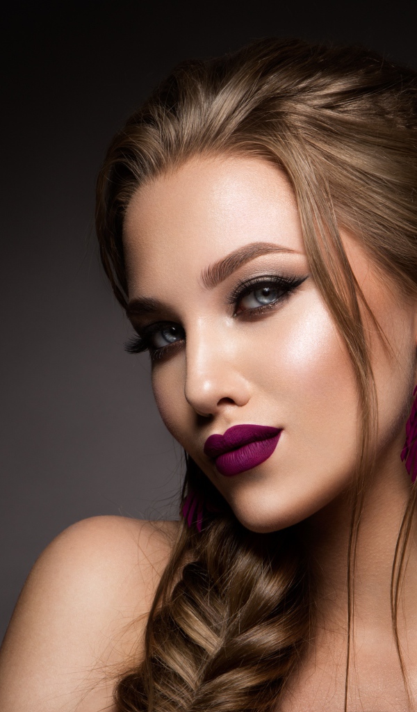 Девушка с ярким макияжем и косой на сером фоне