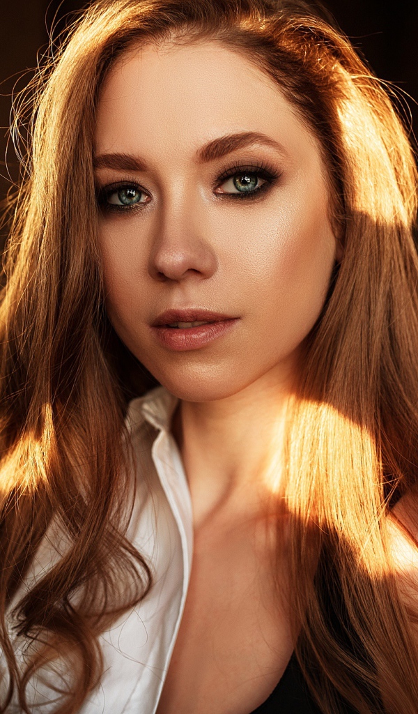 Лучи солнца нападают на волосы голубоглазой шатенки 