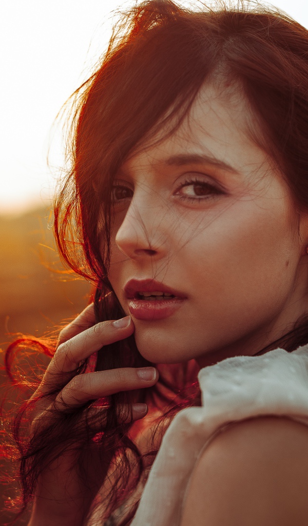 Ветер развивает волосы молодой девушки 