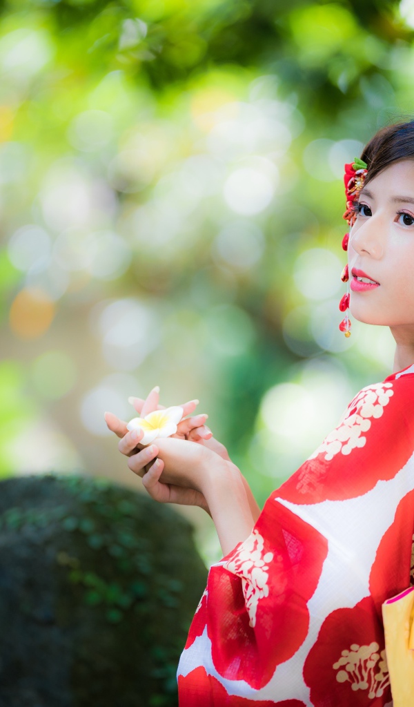 Молодая девушка азиатка в кимоно с цветами в волосах 