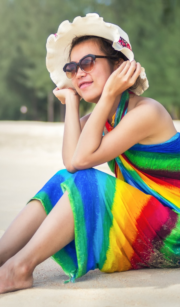 Молодая азиатка сидит на берегу с кокосом