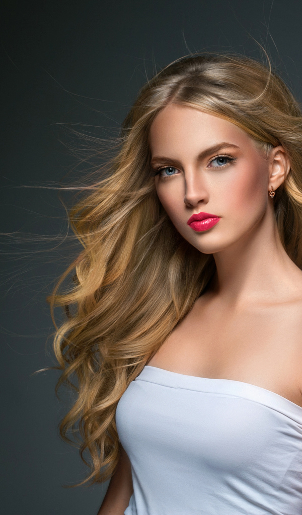 Молодая красивая голубоглазая блондинка на сером фоне