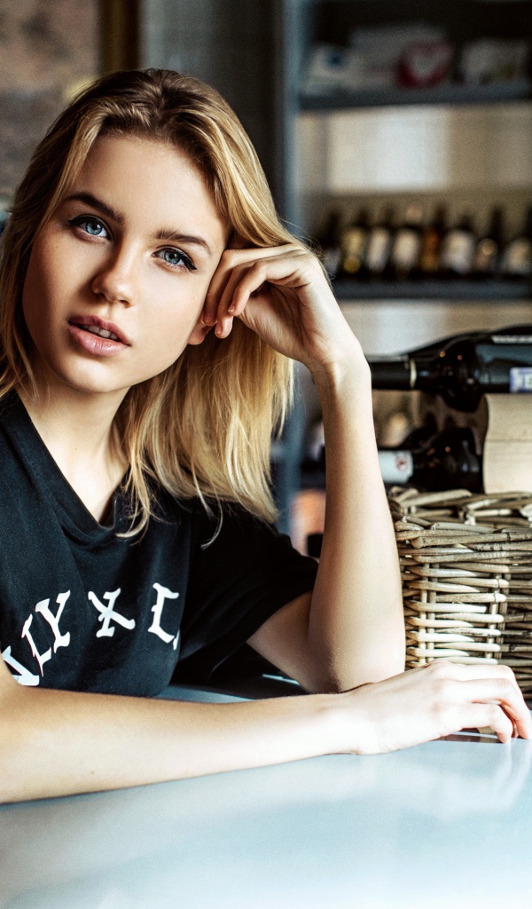 Молодая голубоглазая девушка сидит в кафе