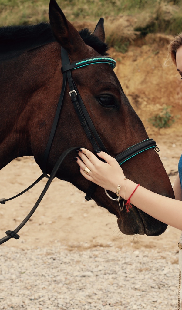 Молодая девушка блондинка с коричневой лошадью 