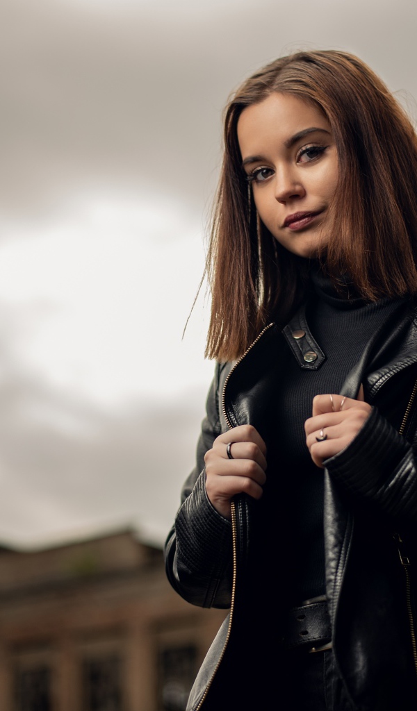 Молодая девушка в кожаной куртке на фоне грозового неба